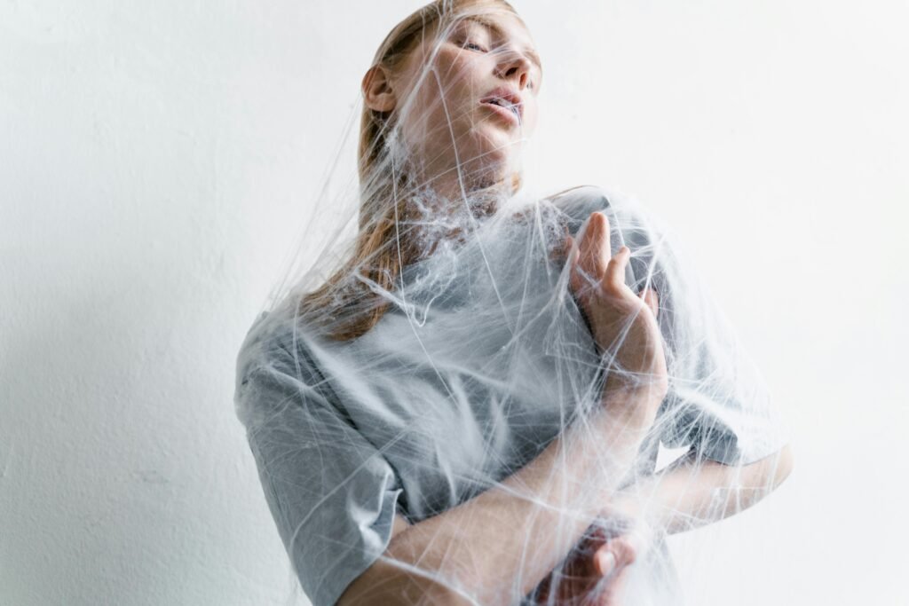 pexels-photo-8458915-8458915 A woman enveloped in spider webs, representing anxiety and helplessness in an artistic conceptual shot.